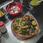 Delicious Mexican tacos with fresh toppings and sauces on a street food stall.