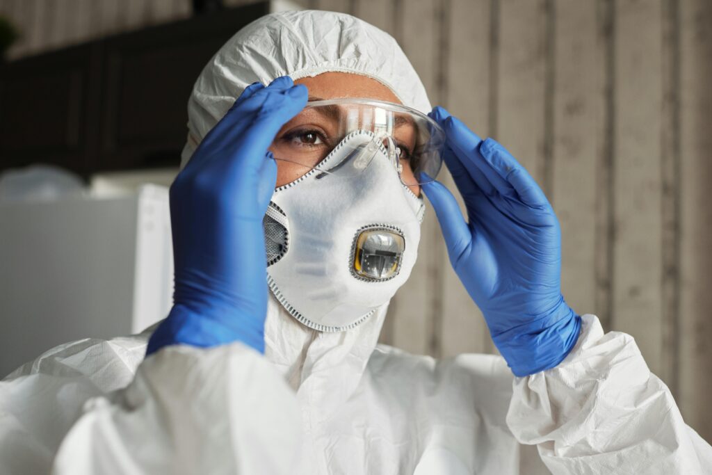 Close-up of healthcare worker wearing protective mask, gloves, and goggles during COVID-19 pandemic.